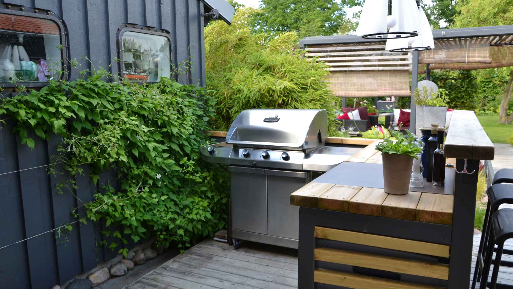 Covered outdoor kitchen with grill, counters, seating, and durable stone finishes